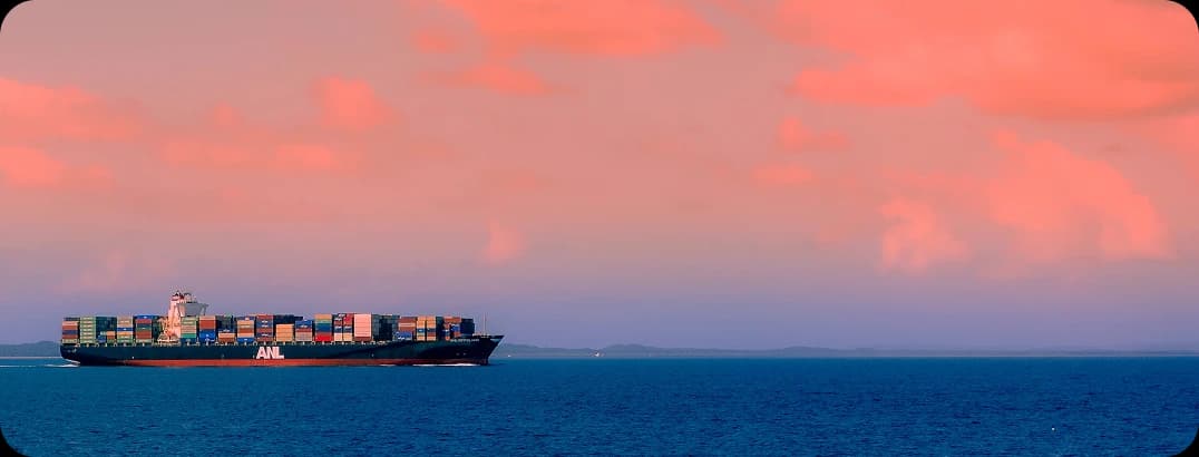 Container ship sailing on the ocean at sunset with cargo containers on deck